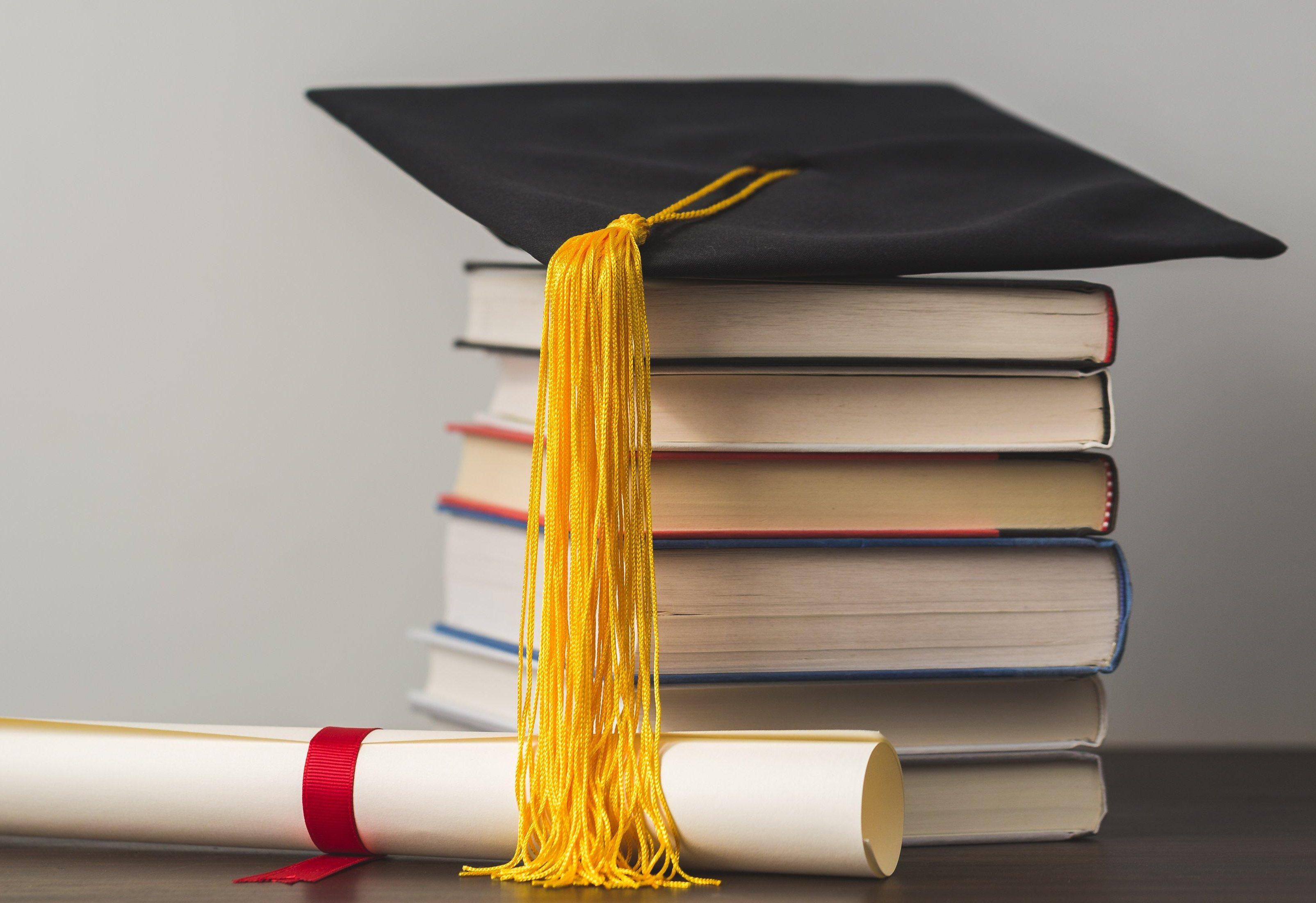 Grad cap diploma and stacked books